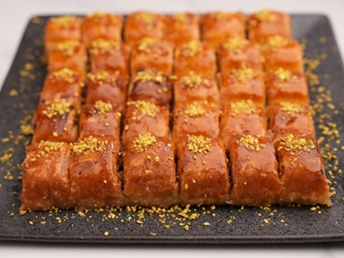 A tray of Persian-style baklava from Laleh Bakery, the best Persian bakery in North Vancouver—featuring golden, syrup-soaked pastry squares topped with crushed pistachios.